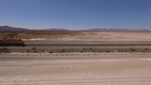 Aerial of a freight train pulling through a rural desert area