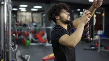 Young man exercising on multistation at gym, closeup.