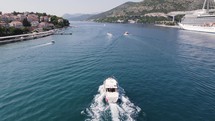 Aerial Tracking shot: boat sailing Dubrovnik port, Adriatic Sea backdrop