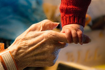 infant holding an elderly hand 