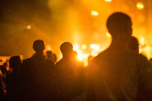 silhouettes of people standing under stage lights at a concert 