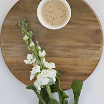 latte and white flowers on a cutting board against a white background 