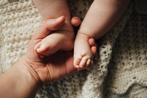 a mother holding a newborns feet 