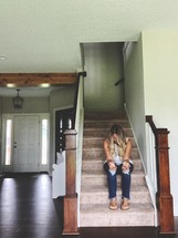 woman sitting on steps in an empty house praying 