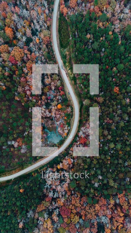 aerial view over a highway through a fall forest 