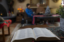 The Bible and people in the background at a home study meeting