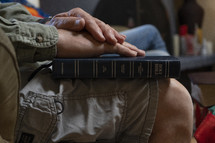 A mans hands upon his Bible at a home study group meeting