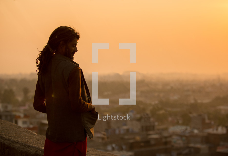 Man standing on a balcony outside overlooking the city of Jaipur.