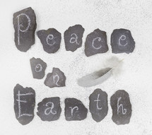 "Peace on Earth" letters in the snow with a feather.