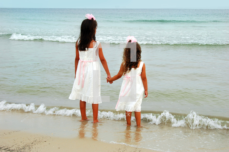 sisters holding hands on a beach 