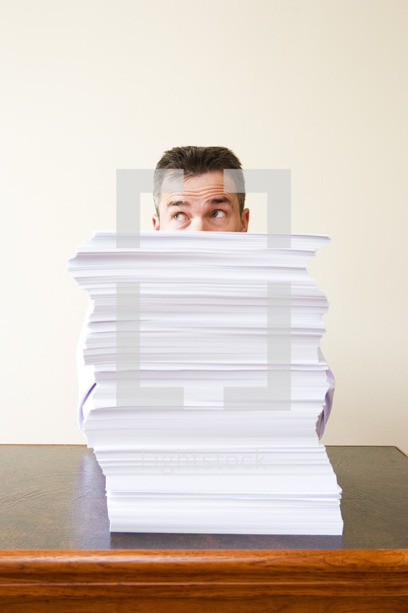 Caucasian businessman behind a stack of paper