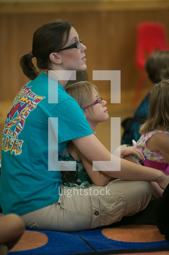 child sitting in her mother's lap during a children's ministry