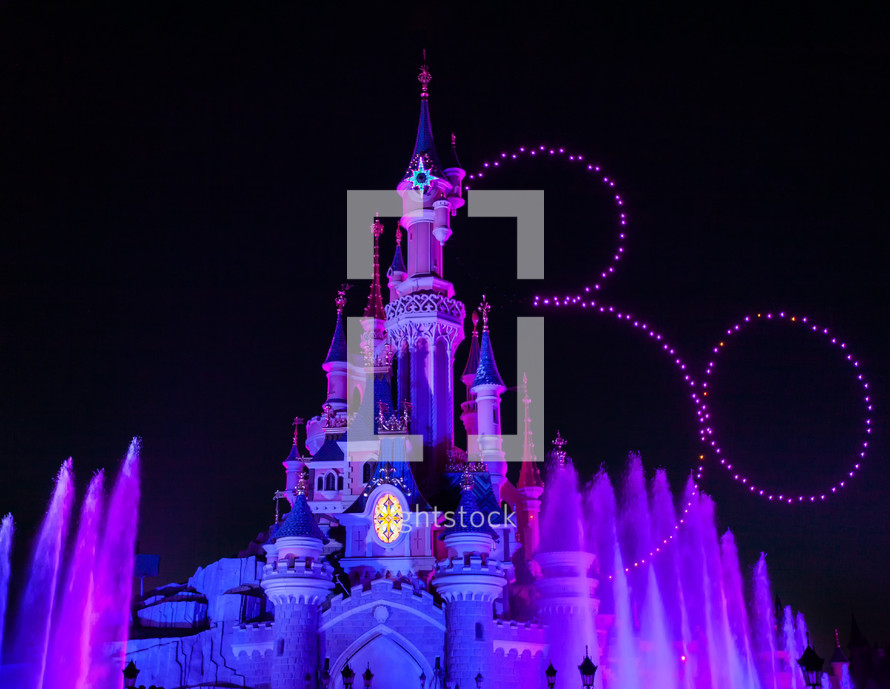 Paris, France - June 02, 2023: Illuminated castle for the 30th anniversary show at Disneyland Paris Park. Drones draw the thirty and the silhouette of Mickey Mouse in the sky.