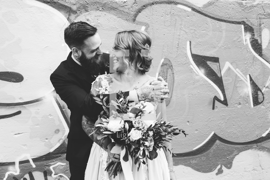 bride and groom hugging in front of a graffiti covered wall 