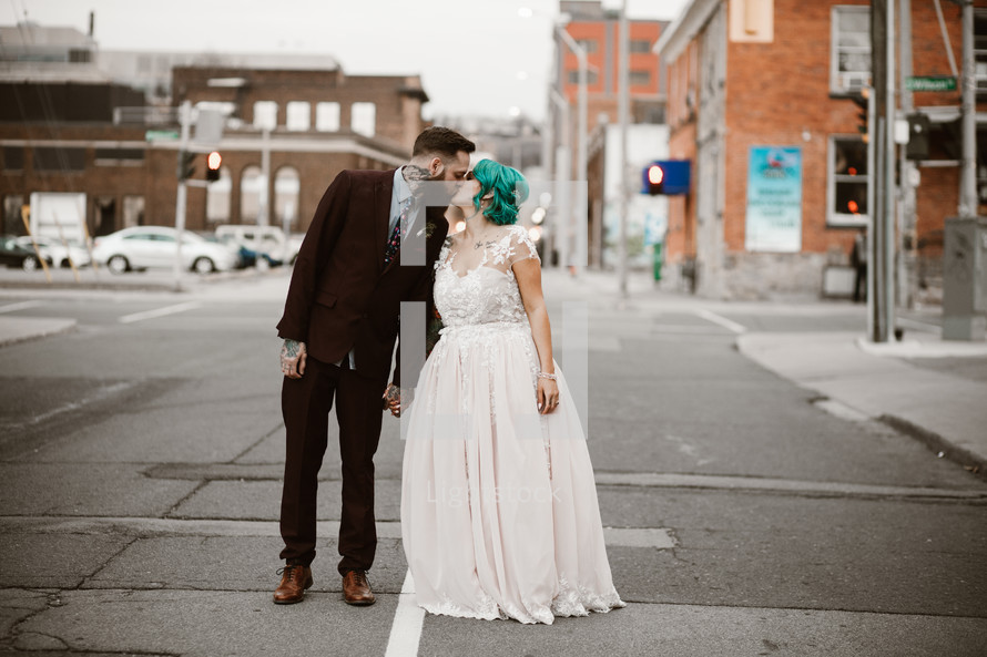 bride and groom in the middle of a street kissing 