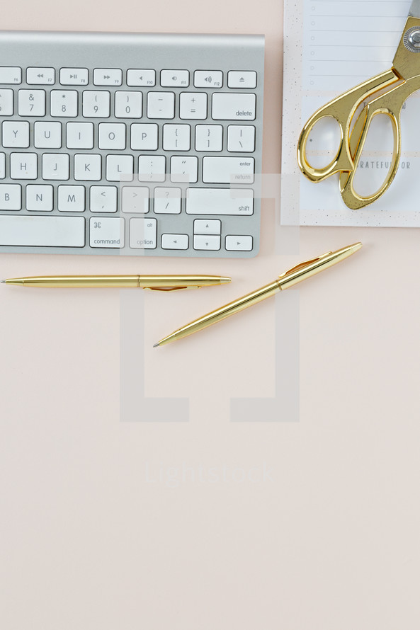 computer keyboard, gold pen, gold scissors, and notepad 