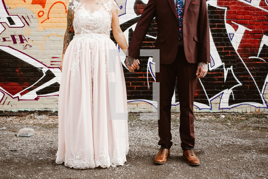 a bride and groom standing in front of a graffiti covered wall 