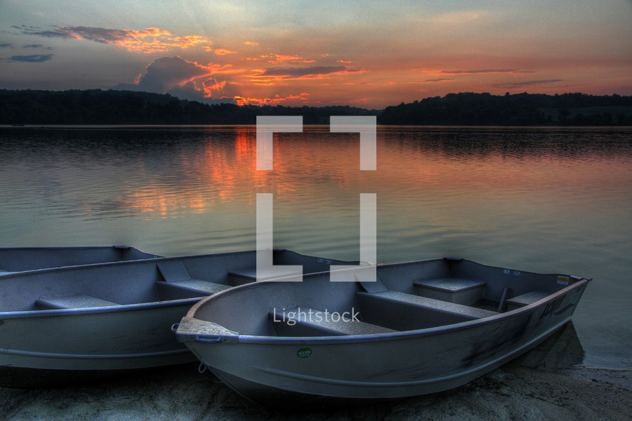 boat resting on the shore of a lake at sunset 