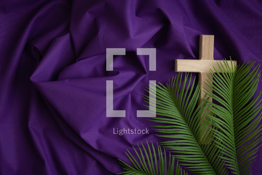 Wood cross and palm leaves on a purple background