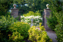 Cross monument and gate between stone pillars at the entrance of an Irish Garden 
