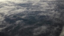 View of earth and clouds from airplane window while flying in cinematic slow motion.
