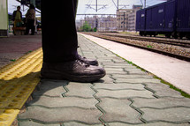feet standing waiting at a train station 