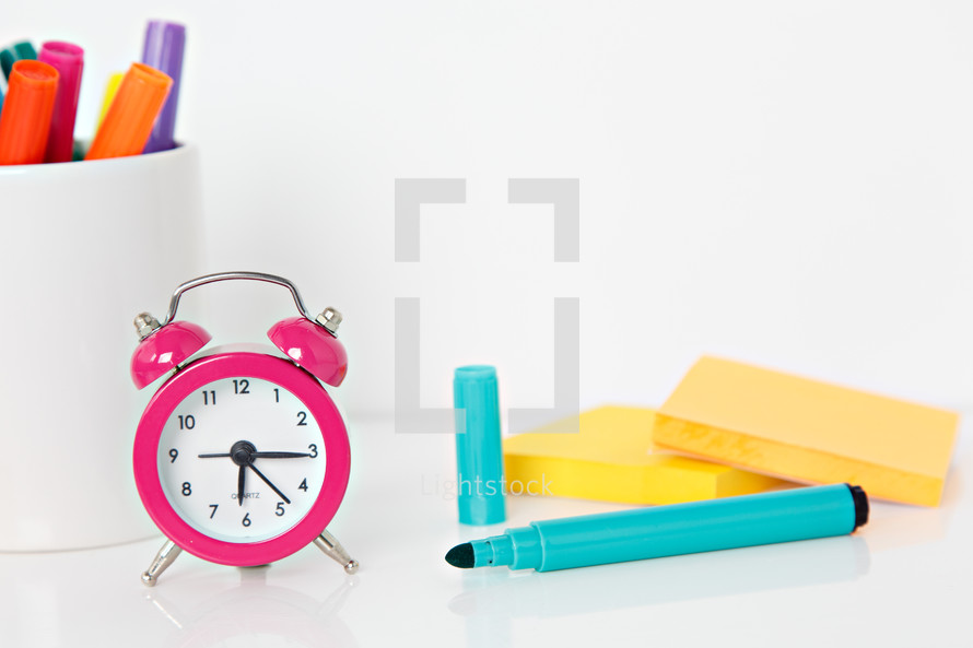 alarm clock and a mug of markers 