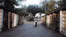 toddler boy riding a bike on a wooden path 