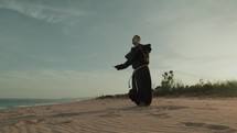 Religious Monk Does Jump Rope On The Soft Sand Beach