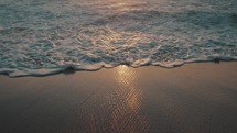 Close up slow motion shot of reflection of the setting sun in the wild waves of the pacific ocean on the sandy beach La Punta in Puerto Escondido Mexico. 
