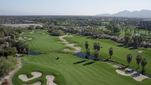 Drone shot captures the breathtaking beauty of a sprawling golf course, showcasing its meticulously maintained fairways, challenging greens, and the natural beauty that surrounds it. 