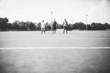 three men standing on a football field 