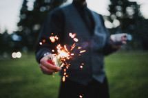 man holding a sparkler and a lighter