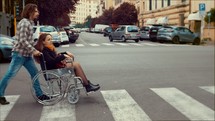 a man pushing a woman in a wheelchair across a crosswalk 