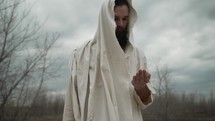 Jesus Christ wearing white tunic or bible prophet or religious man holding as stone in his hand.