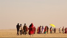 men and women waling through the desert 