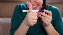 an excited woman looking at a positive pregnancy test 