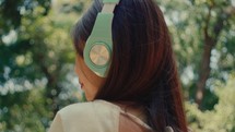 from view of young female model wearing headphone in the park listening alone to music 
