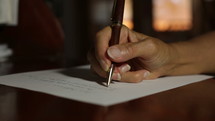 A woman writing a letter by hand with pen and paper