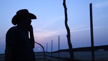 silhouette of a cowboy talking on a cellphone at sunset 