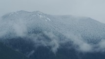 Clouds slowly move in front of snow tipped mountains in the Pacific Northwest