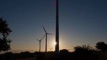 Silhouette of a wind power plant generator at sunset on the mountains
