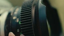 Female hand close up while turning the focus wheel on old fashioned vintage retro film camera lens 