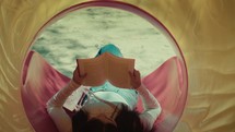 Woman relaxing while reading a novel book and listening to the music sit inside a park slide