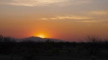 Time lapse of an orange sunrise over desert mountains