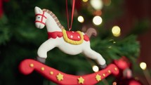 White horse decoration hanging on a Christmas tree with snow falling 