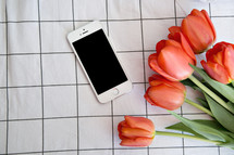 cellphone and tulips on table cloth 