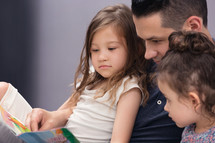 Father and Two Daughters Reading a Story