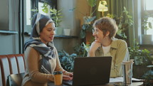 Woman in Hijab Speaking with Female Colleague in Coworking Office
