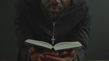 Clergyman Holding Opened Bible and Reading Prayer Aloud